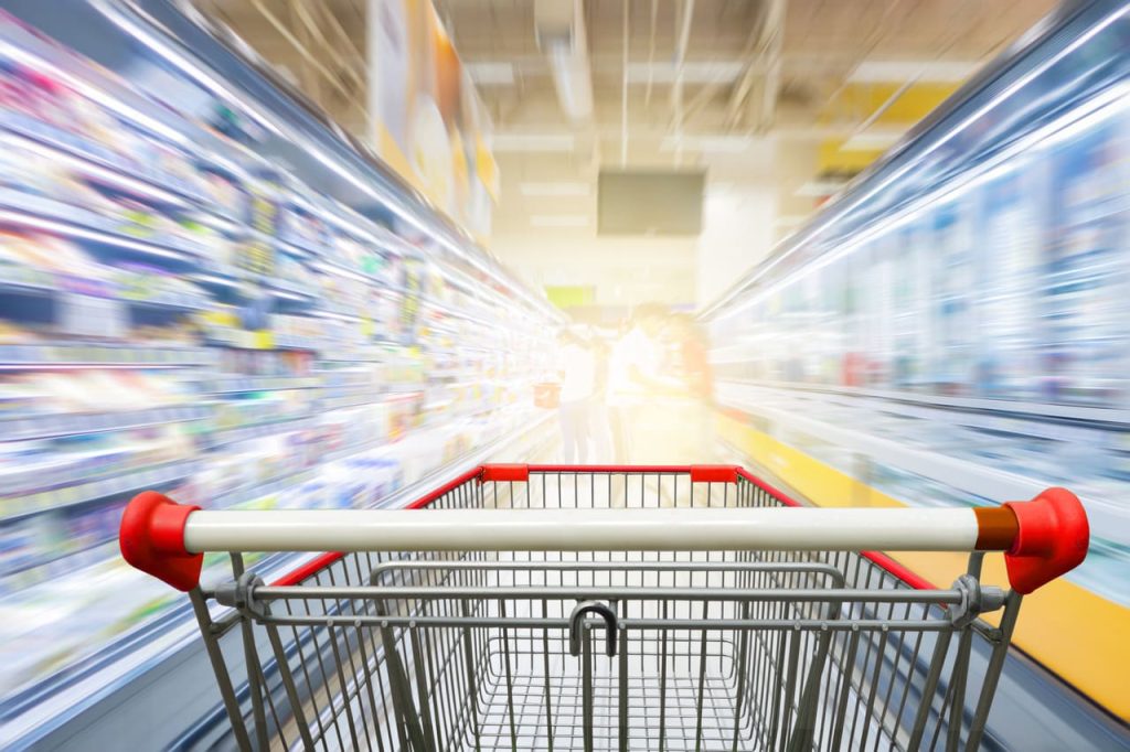 A shopping trolley among the shelves of a supermarket.
